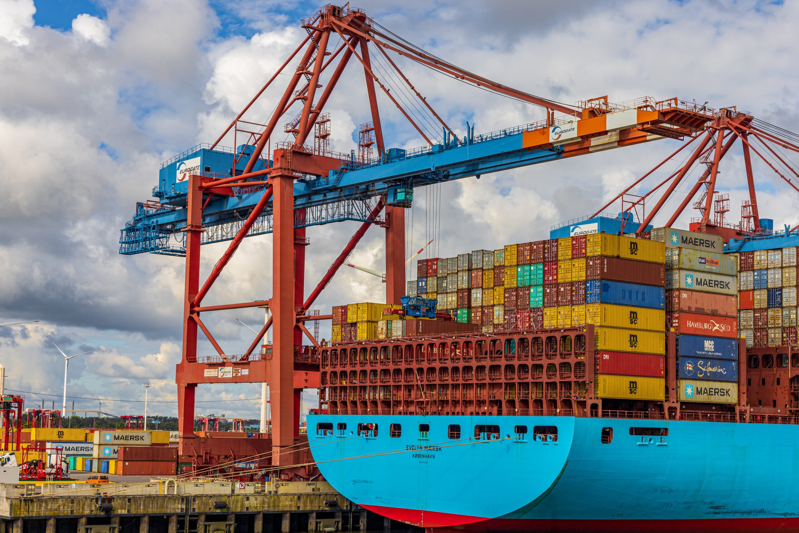 Large ship with crane adding transportation boxes on it