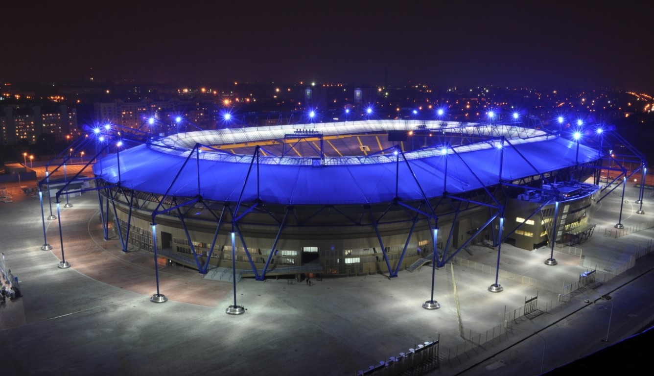 Ariel shot of the JMA Wireless Dome at night with blue lights illuminating the arena.